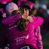 a woman in a pink shirt hugging another woman