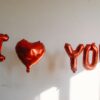 balloons spelling out i love you in front of a white wall