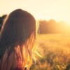 woman wearing black camisole top walking on grass field during sunrise