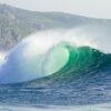 a large wave is breaking in front of a mountain