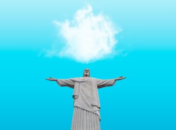 woman in beige dress raising her hands under blue sky and white clouds during daytime