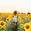 woman standing between sunflower field during daytime