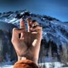 a person making a peace sign in front of a mountain