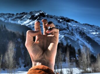 a person making a peace sign in front of a mountain