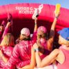 a group of women in pink shirts standing in front of a pink inflatable