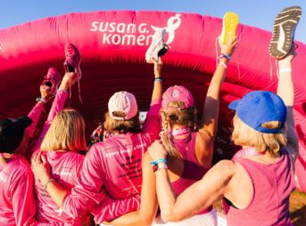 a group of women in pink shirts standing in front of a pink inflatable