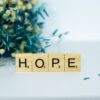 a wooden block that says hope next to a bouquet of flowers