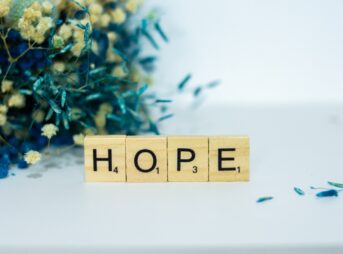 a wooden block that says hope next to a bouquet of flowers