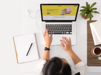 a person sitting at a desk with a laptop and a coffee cup